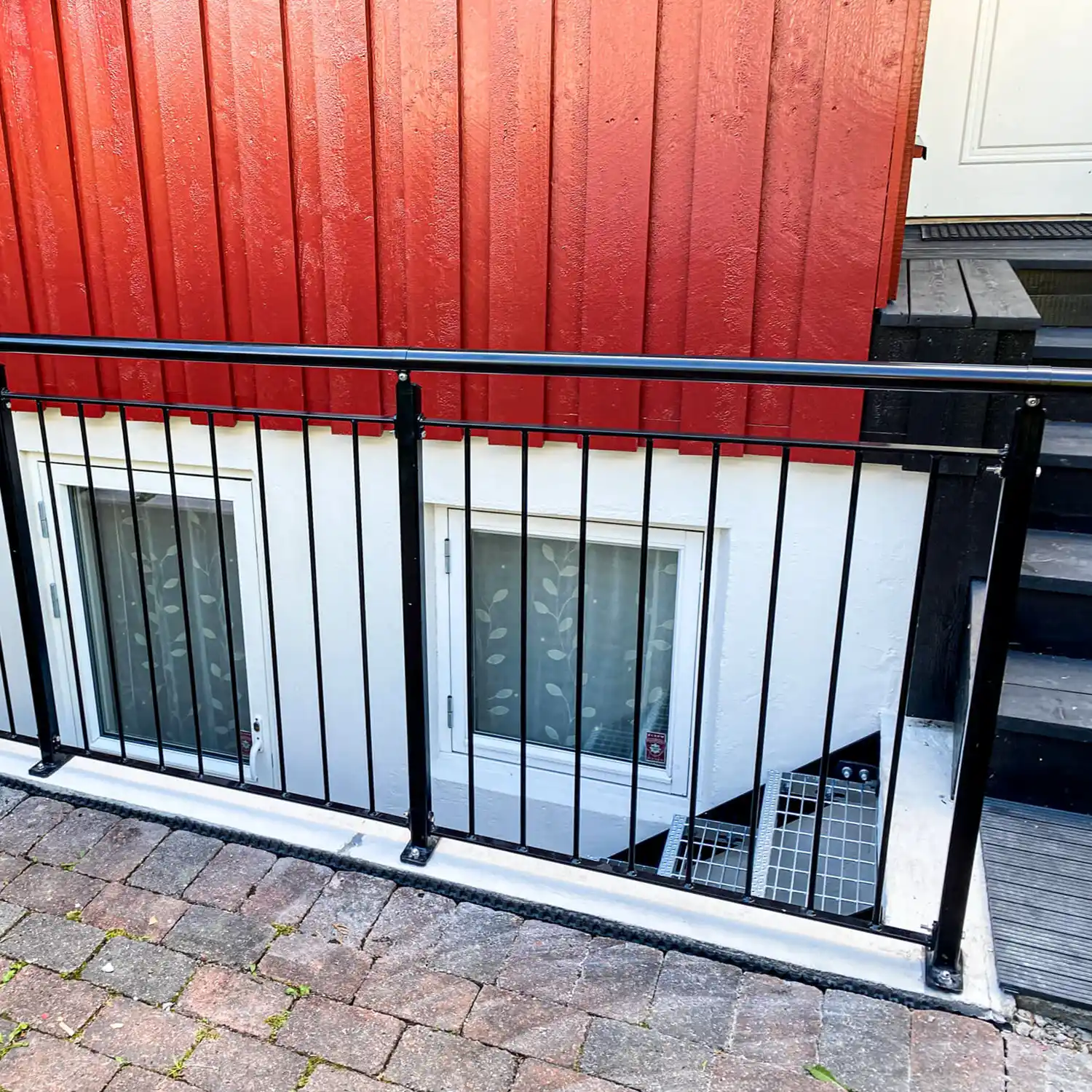 Svartlakkert rekkverk ved trapperom med vertikale spiler.