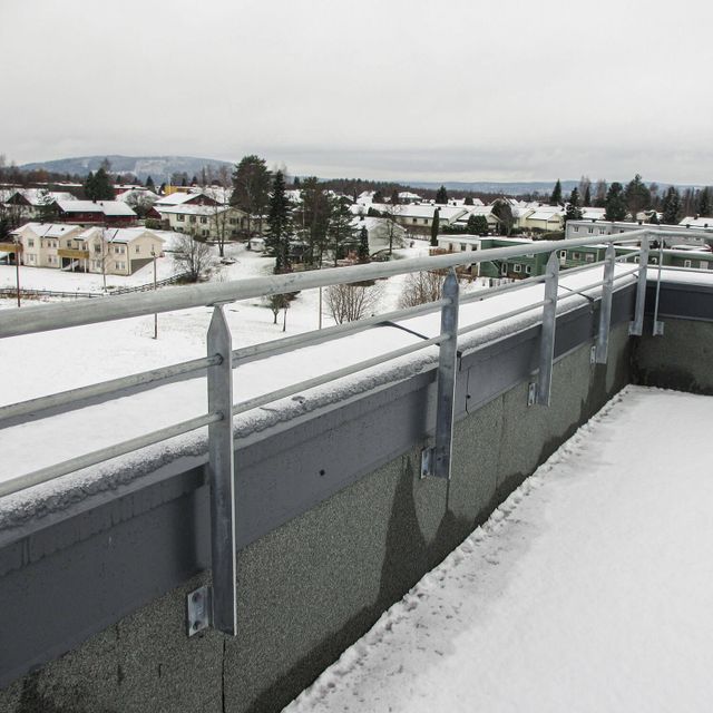 Lavt metallrekkverk som forhøyning på mur. Horisontale rør.