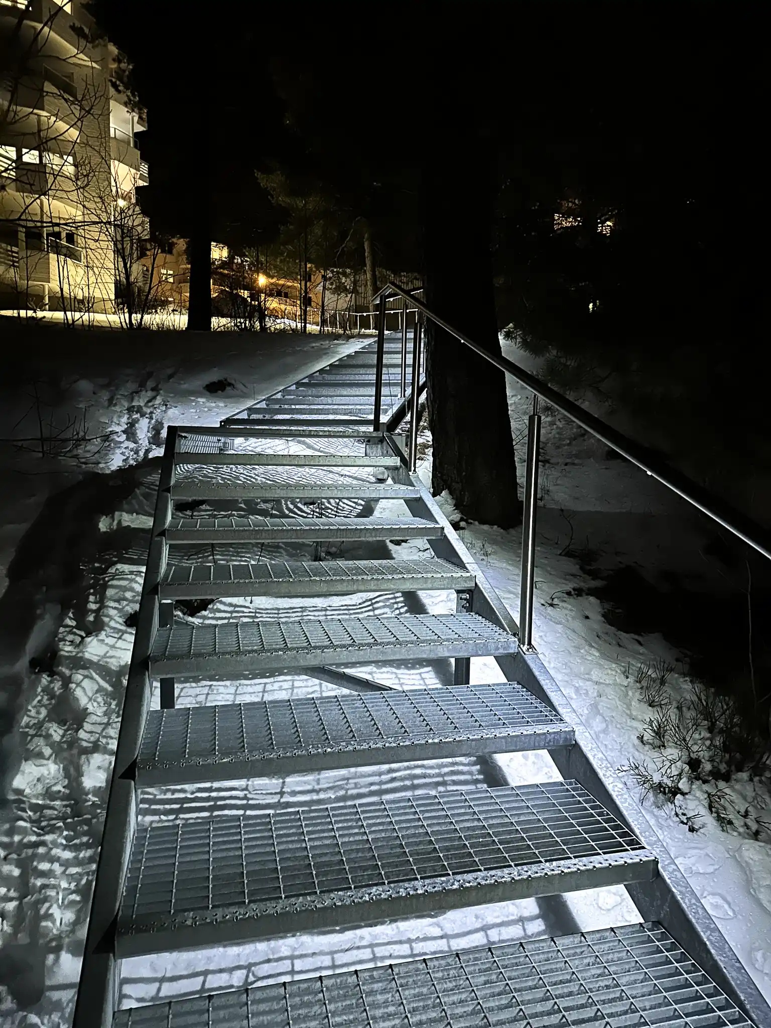 Terrengtrapp i vintermørket med håndløpere og LED-belydsning.