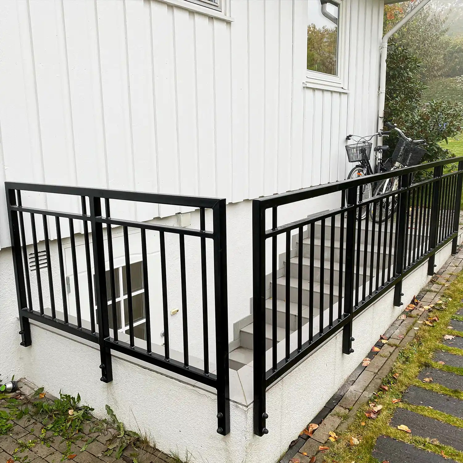 Svartlakkert rekkverk rundt trapperom med vertikale spiler.