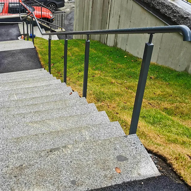 Lakkert sidemontert håndløper i trapp.