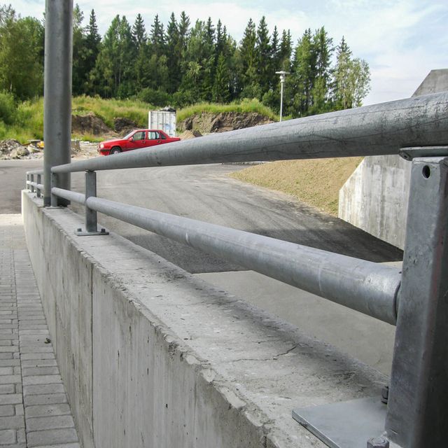 Lavt metallrekkverk som forhøyning på mur. Horisontale rør.